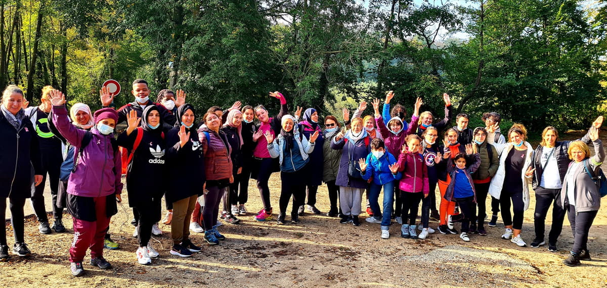 Groupe de femmes en demi-cercle à l'orée d'une forêt.